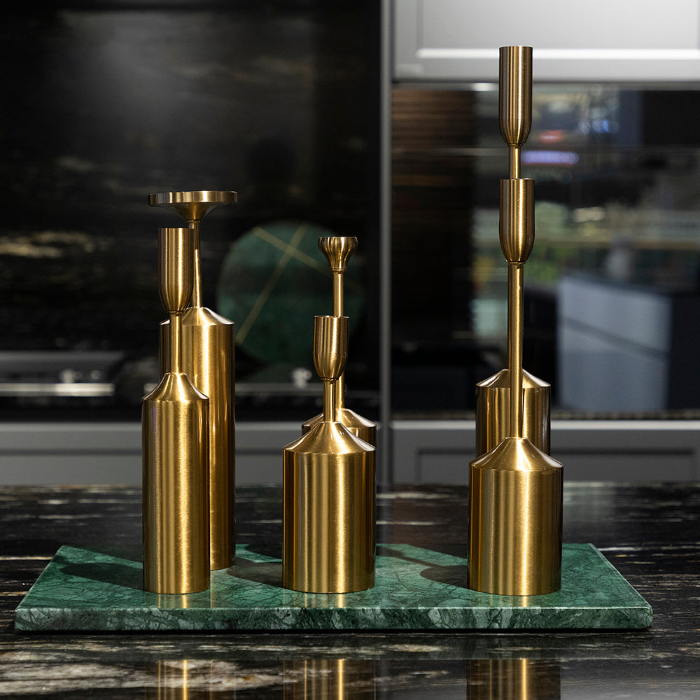 Set of gold candle holders on a green marble base with a blurred background