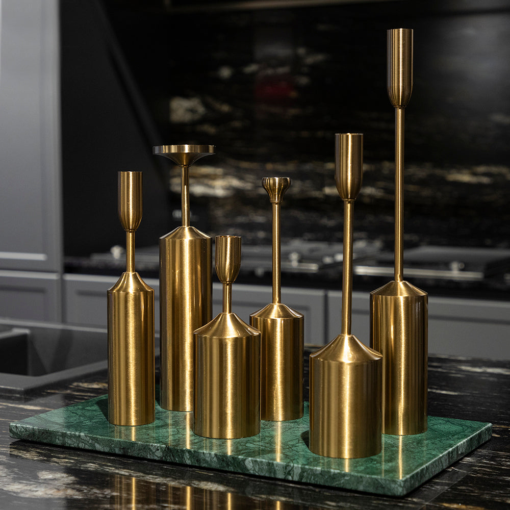 Set of gold candle holders on a green marble base against a dark background