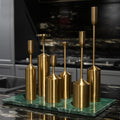 Set of gold candle holders on a green marble base against a dark background