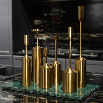Set of gold candle holders on a green marble base against a dark background